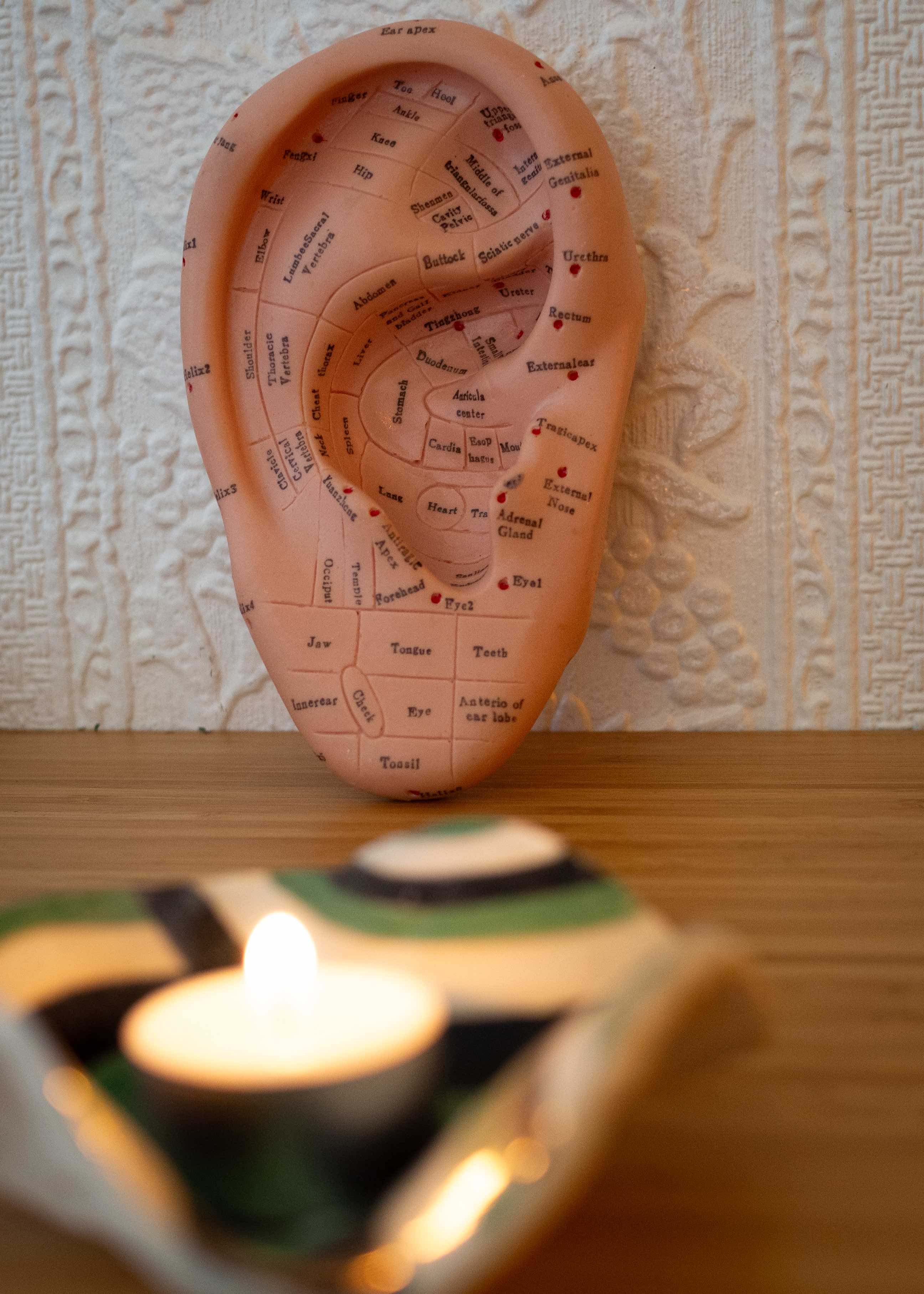 Ear Reflexology chart in front of a relaxing candle